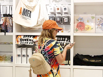Photo of a young girl wearing an orange ballcap looking at AMFA merchandise in the Museum Store.