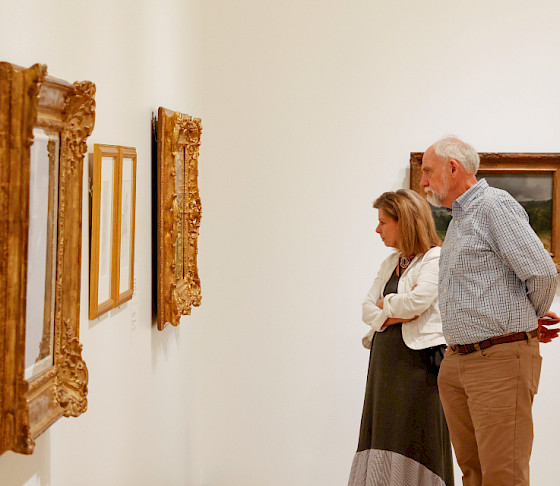 Photo of a couple looking at art hanging on a wall in an art gallery.