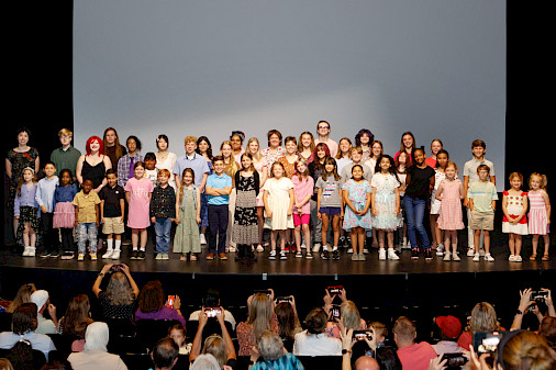 Photo of a group of children smiling on a stage.