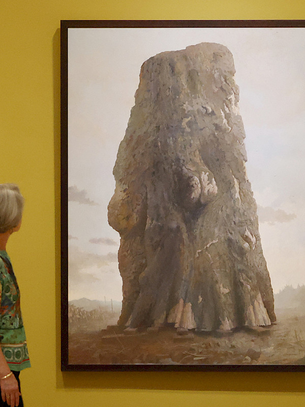 Photo of a woman looking at a large painting in an art gallery.