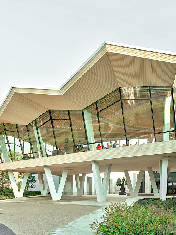 Photo of the Courtyard Entrance to the Arkansas Museum of Fine Arts. People are visible in the Cultural Living Room on the second floor.