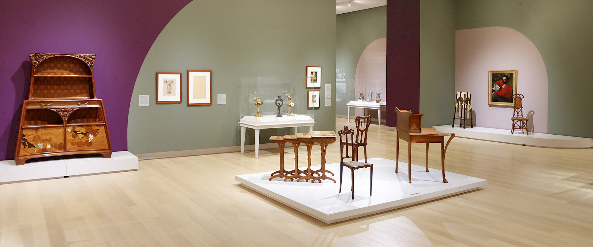 Photo of several displays of Art Nouveau furniture in a gallery at the Arkansas Museum of Fine Arts.