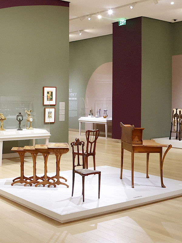 Photo of several displays of Art Nouveau furniture in a gallery at the Arkansas Museum of Fine Arts.