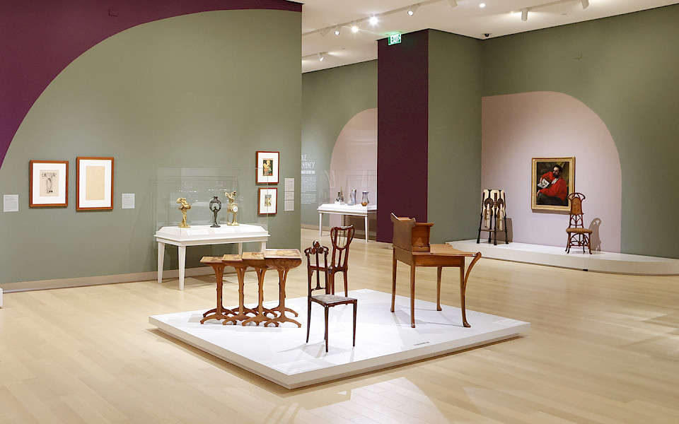 Photo of several displays of Art Nouveau furniture in a gallery at the Arkansas Museum of Fine Arts.