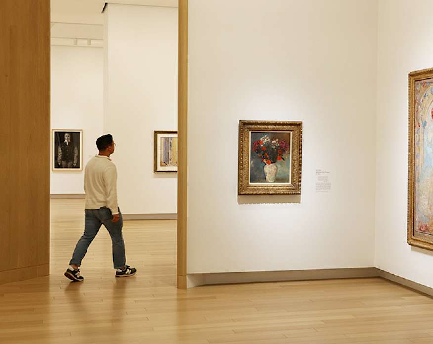 Photo of a young man walking through a dimly lit art gallery.