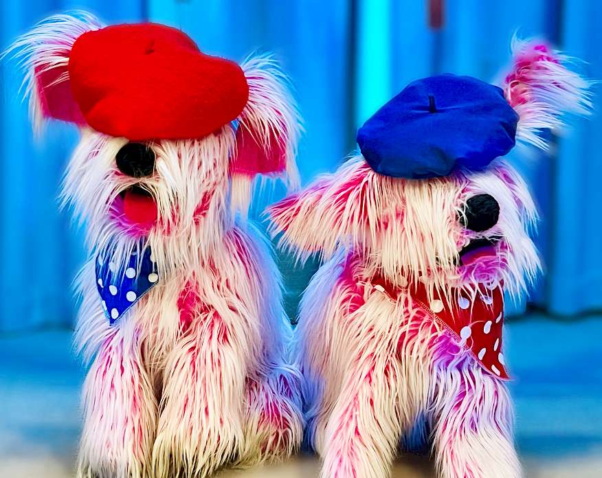 Photo of two pink dog puppets wearing bandanas and berets.