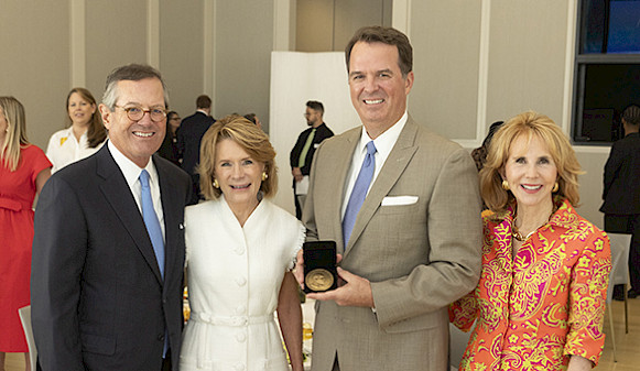 Photo of Warren Stephens, Harriet Stephens, Stan Hastings, and Terri Erwin. Stan Hastings is smiling and holding a medal.