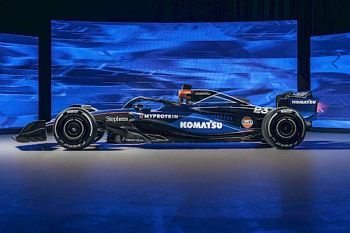 Photo of a Formula 1 racecar in a showroom in front of a blue background.