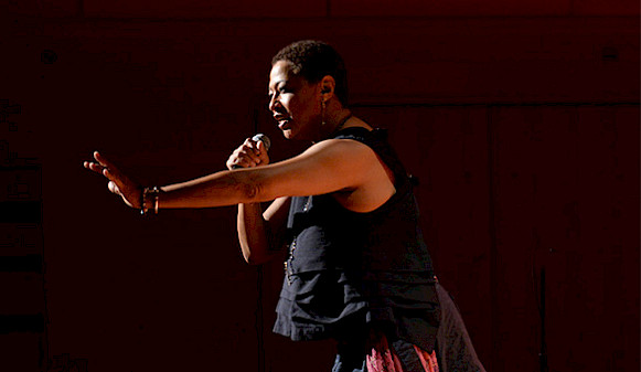 Photo of Ms. Lisa Fischer singing into a microphone on stage. Photo by Christina Alonso.