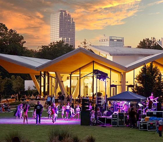 Photo of the Event Lawn outside the Arkansas Museum of Fine Arts where children and families are watching a concert at sunset.