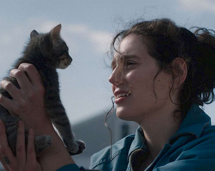 Film still from the movie Sorry Baby showing a woman holding a kitten to eye level.