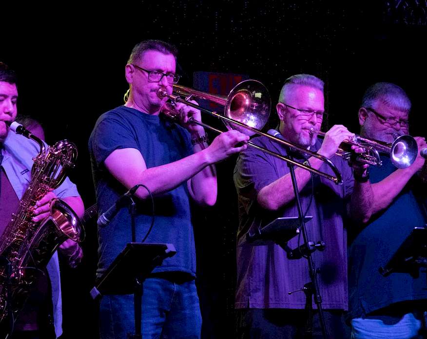 Photo of four men on a stage playing brass instruments.