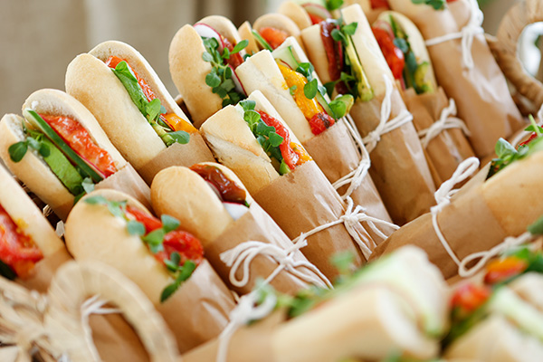 Photo of a display of gourmet sandwiches wrapped in brown paper and white string.