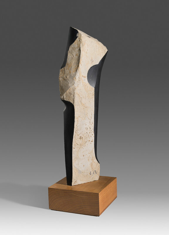 Photo of a wooden sculpture in the shape of an abstract column painted black and white.