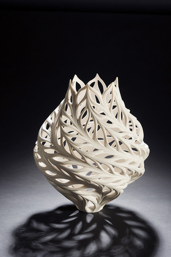 Photo of a sculpted white vase with an intricate cut-out pattern.