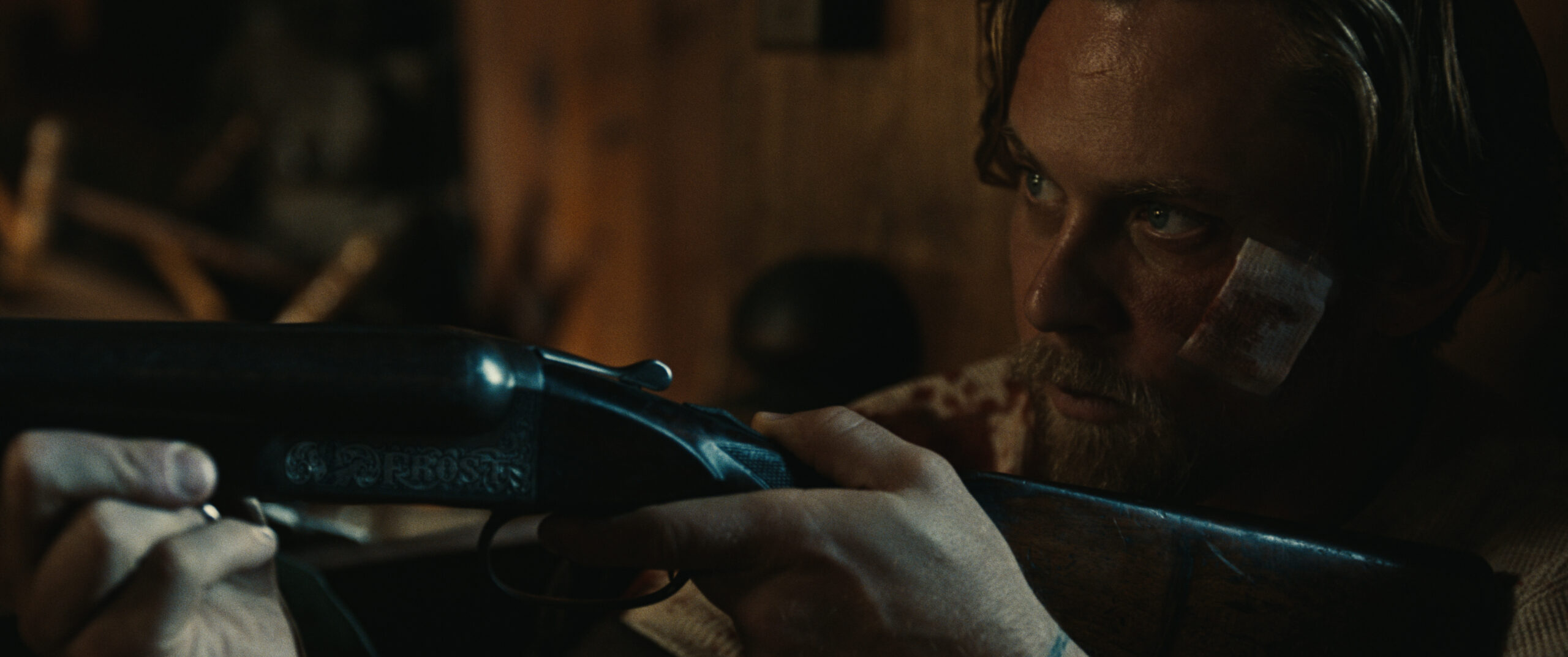 Film still from the movie Violet Ends showing a close up of a man with a bandaged face holding a rifle.