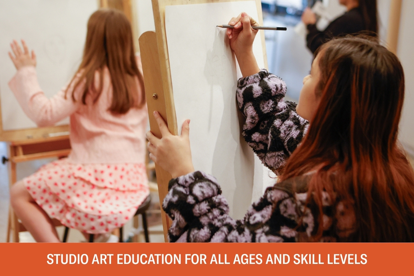 Photo of two young girls drawing at art easels in an art studio at AMFA. Below the photo is text that reads studio art education for all ages and skill levels.