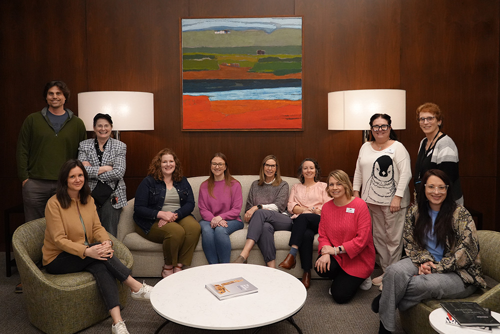 Photo of a group of people posed sitting in a lounge area and smiling.