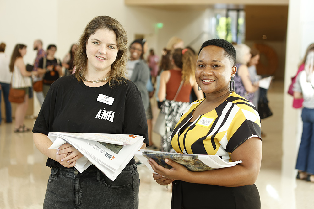 Photo of two educators smiling and wearing name tags in the Atrium of the Arkansas Museum of Fine Arts.