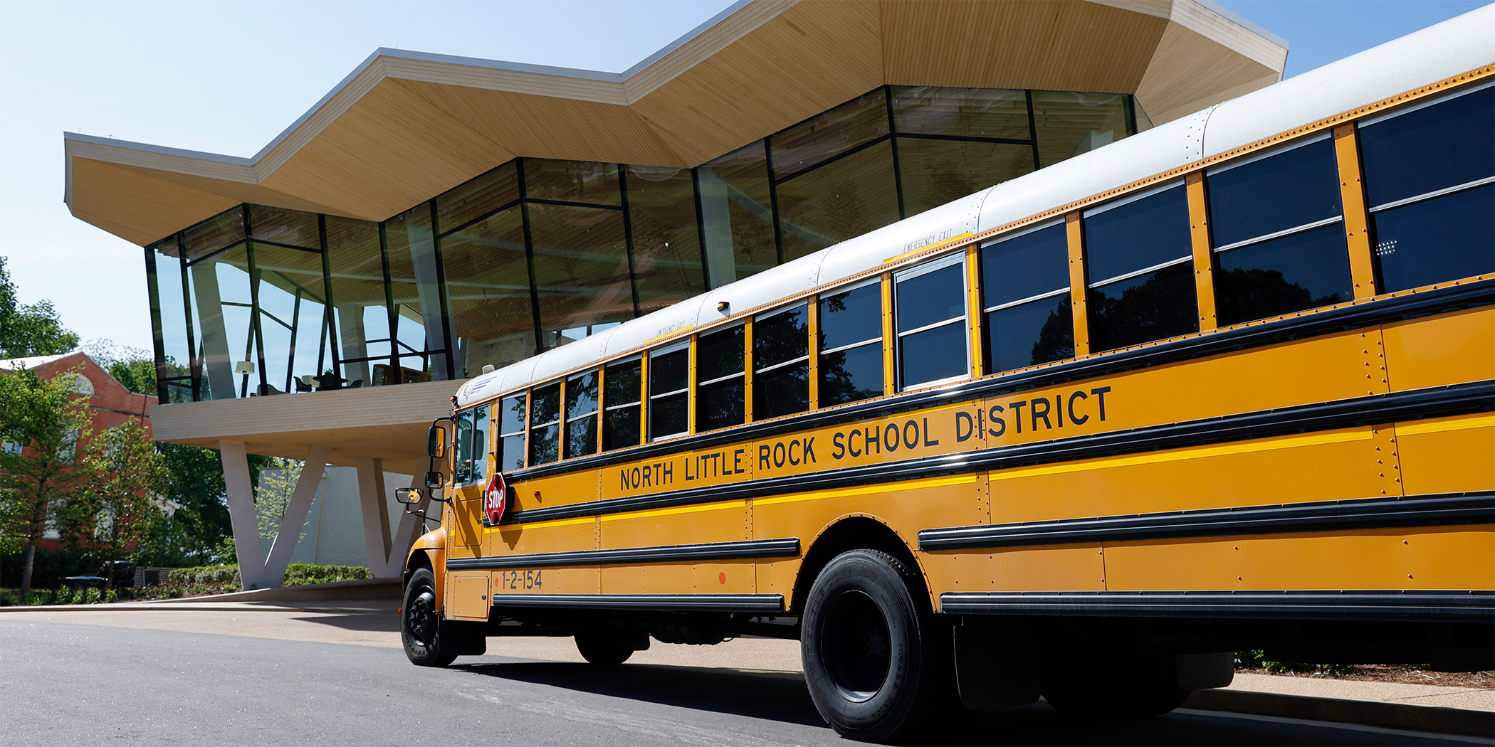 Photo of a school bus parked in front of the Courtyard Entrance to the Arkansas Museum of Fine Arts. The bus is painted with the words North Little Rock School District.
