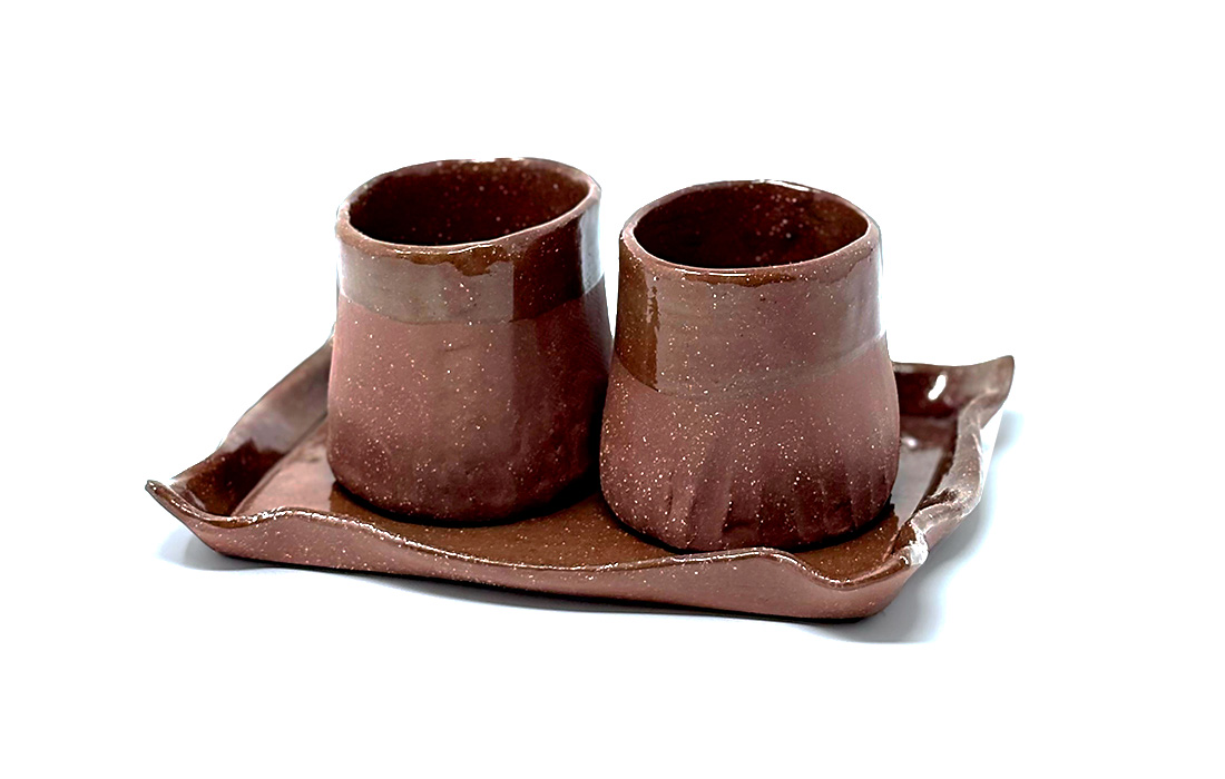Photo of a glazed brown handmade ceramic tray holding two glazed brown handmade mugs.
