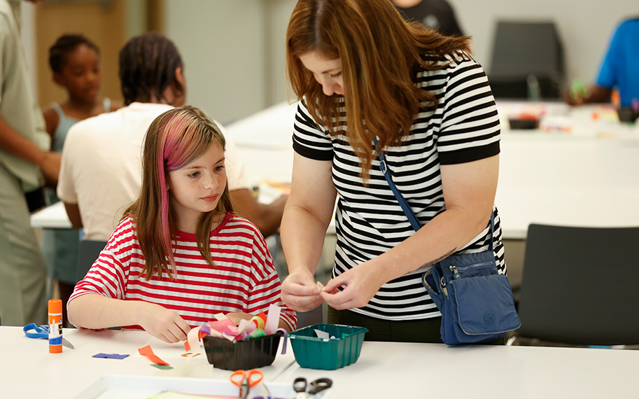 Photo of a woman and young girl wearing striped shirts and doing an art activity in a studio at AMFA.