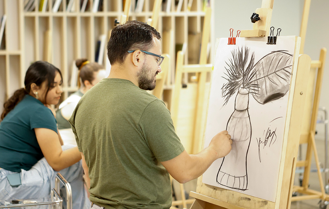 Photo of a man and a woman drawing at easels in an art studio.
