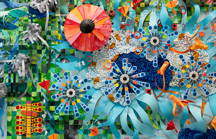 Detail photo of a colorful art installation of hand-cut paper shapes.