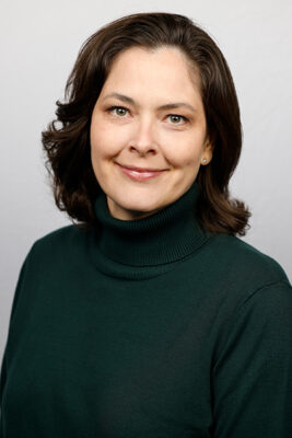 Headshot of a woman with short brown hair wearing a black turtleneck.