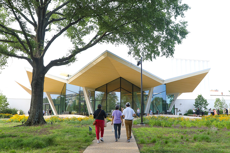 Photo of three people walking through MacArthur Park toward the Arkansas Museum of Fine Arts.