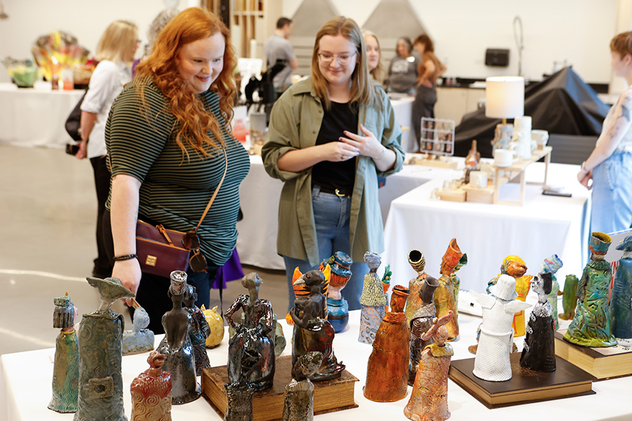Photo of two women looking at small handmade sculptures on a table at the AMFA Art Market.