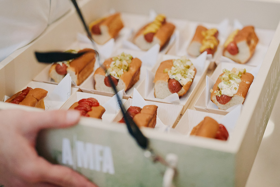 Photo of a dozen miniature hot dogs on a large tray emblazoned with the AMFA logo.