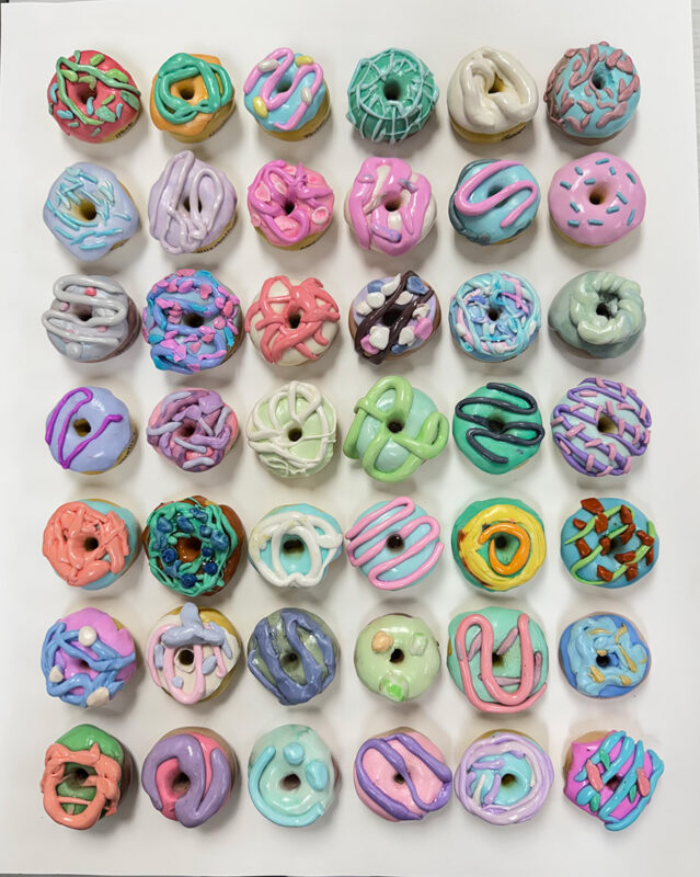 Photo of a series of handmade model magic sculptures shaped and painted like small donuts.