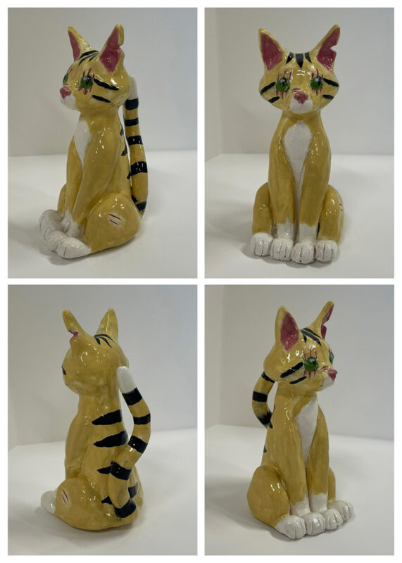 Photo of a ceramic yellow cat with black stripes on its back and tail.