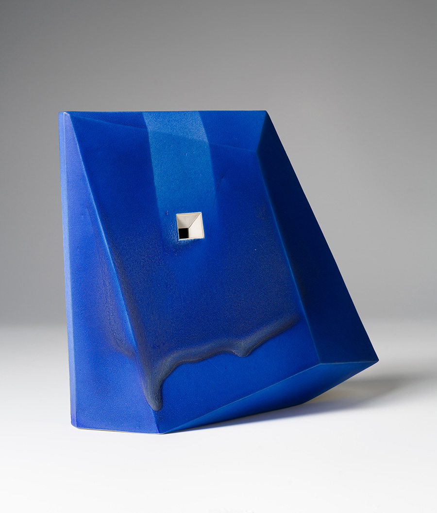 Photo of a small porcelain sculpture in an abstract shape with a blue glaze.