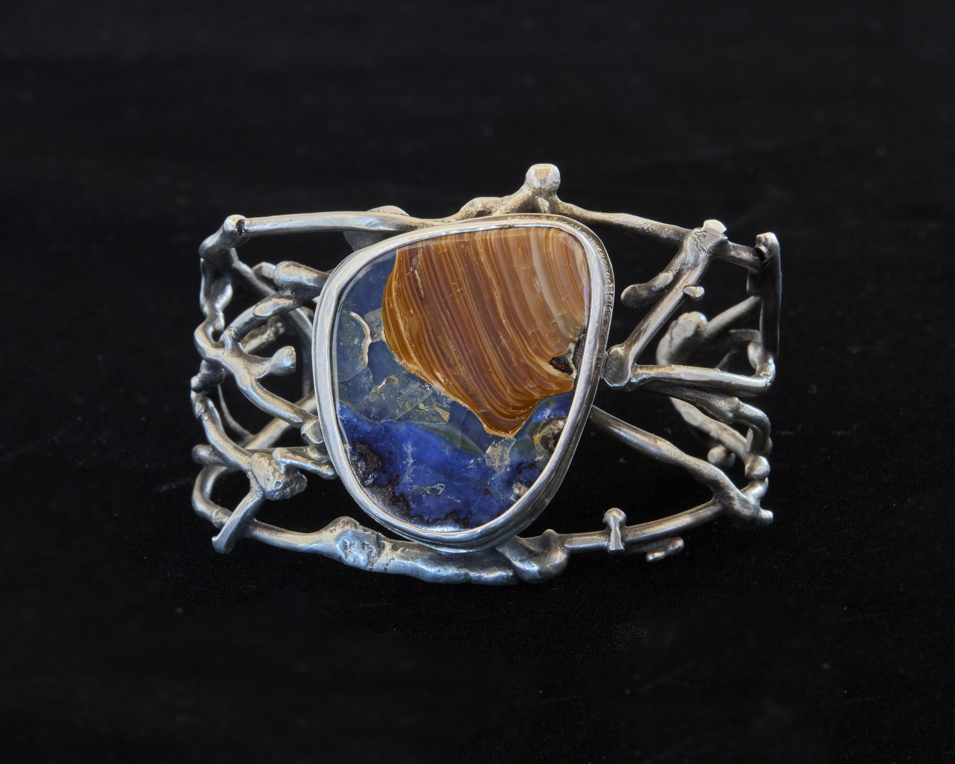 Photo of a handmade metal cuff with a large gemstone in the center.