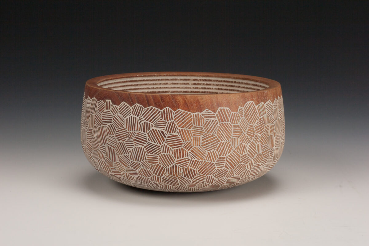 Photo of a turned wood bowl decorated with a white geometric pattern.