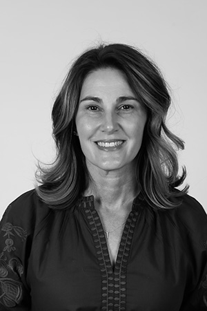 Black and white headshot of a smiling woman with curled shoulder-length hair.