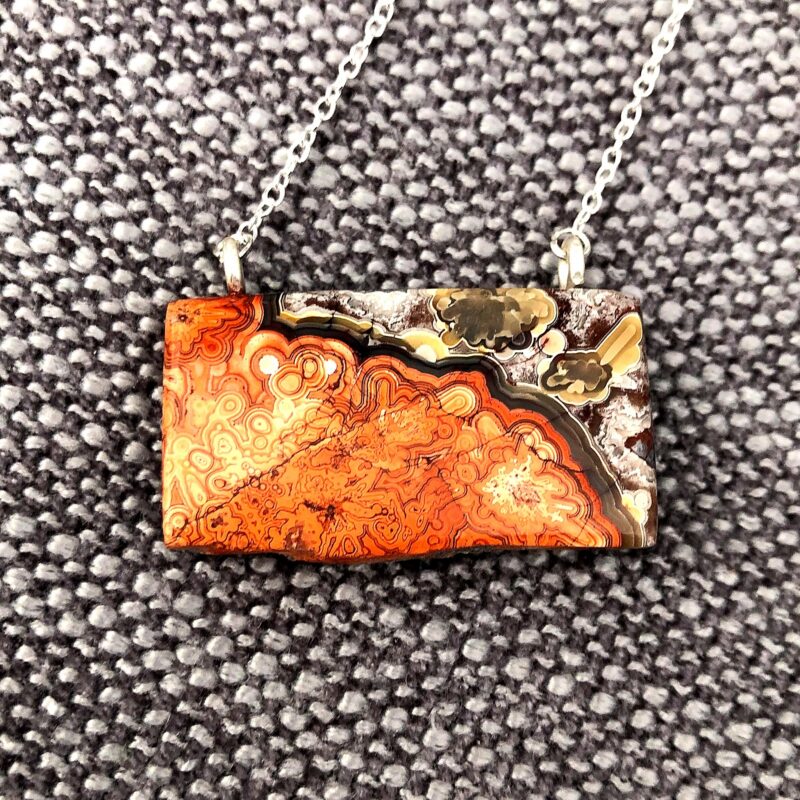 Photo of a silver chain necklace with a coral agate pendant.