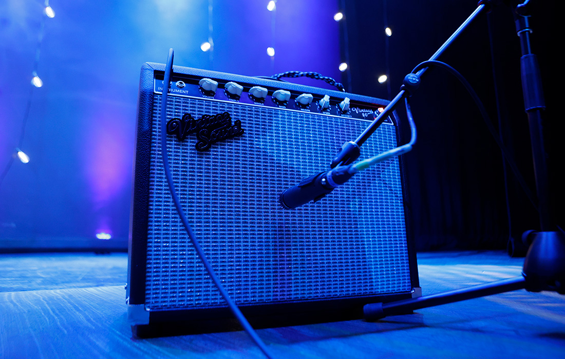 Photo of a microphone next to an amplifier on a dark stage.